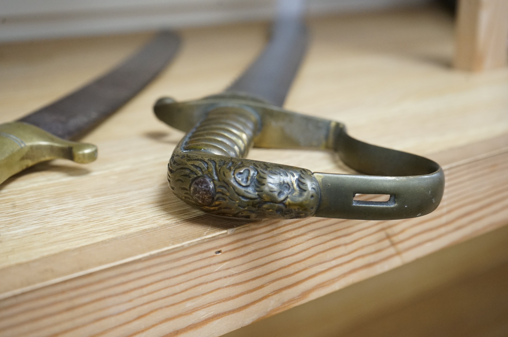 A British Pioneer’s sidearm with brass stirrup hilt, lion’s head pommel and sawback blade, together with an Imperial German sidearm with one piece brass hilt and slightly curved single edge blade